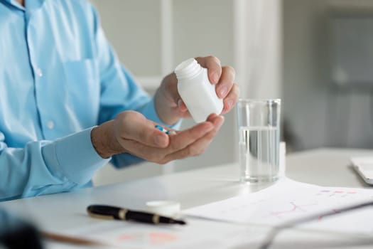 A person taking medicine while feeling sick at their home office emphasizing the importance of health and self-care.