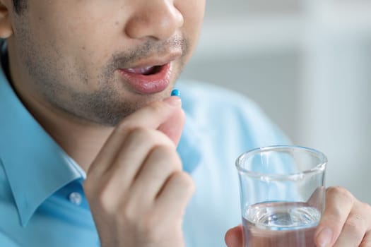 A close-up of a person taking medicine while feeling unwell highlighting the importance of self-care in a home setting.