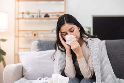 A woman feeling unwell at home wrapped in a blanket facing emotional distress.
