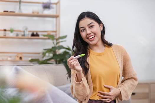 A joyful woman holds a pregnancy test celebrating her news in a warm and inviting home.