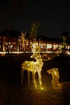 a group of lighted deer statues in a park near the cafe and roaster at night
