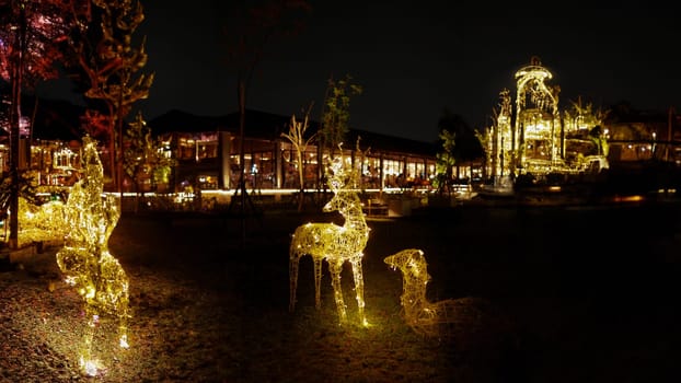 a group of lighted deer statues in a park near the cafe and roaster at night