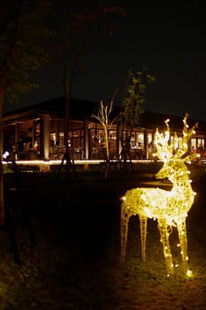 a group of lighted deer statues in a park near the cafe and roaster at night