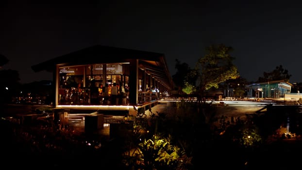 Nighttime view of a modern house with illuminated interiors and surrounding landscape.