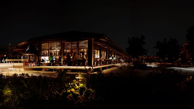 Modern restaurant with illuminated facade at night, surrounded by darkness, offering a cozy dining atmosphere.