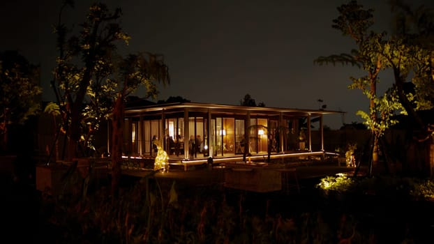 Cozy illuminated cabin at night surrounded by trees, offering a tranquil and inviting atmosphere in the dark night