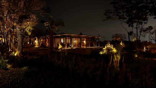 Secluded cabin illuminated at night amidst forest trees, offering a tranquil and cozy retreat in nature.