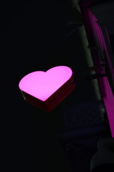 A glowing pink heart sign illuminated against a dark backdrop, beautifully evoking the feelings of love and warmth