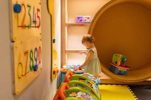 Toddler exploring a vibrant playroom with engaging toys and activity tables, fostering creative growth and learning. Concept of interactive play for early childhood development