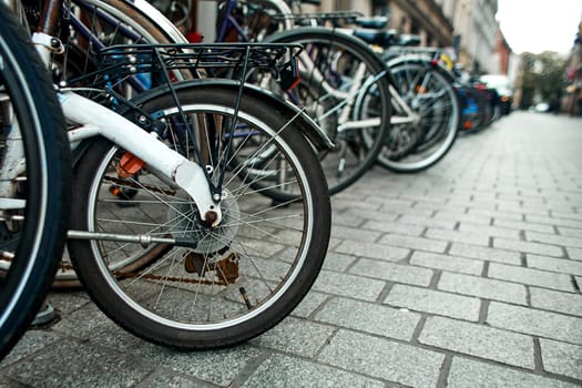 Close-up of a wheel in a row of parked bicycles on the streets of Europe