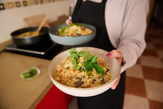 Bowls of freshly prepared vegetable paella are served, showcasing a cozy kitchen ambiance. Ideal for illustrating fresh, nutritious cooking, emphasizing a vegetarian-friendly lifestyle with vibrant flavors.