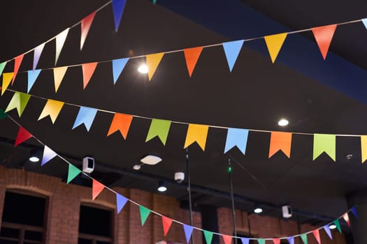 Vibrant and colorful bunting flags hang decoratively in a dimly lit venue, adding a charming festive atmosphere