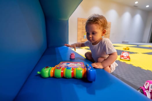 Toddler focused on a toy in a vibrant and interactive playroom full of educational activities. Concept of fun and cognitive growth for children through creative play