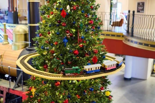 A beautifully decorated and sparkling Christmas tree featuring a delightful toy train along with colorful ornaments