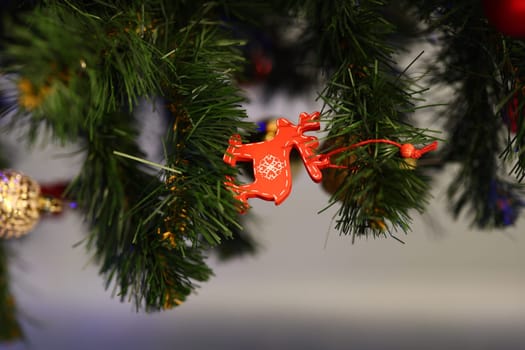 A cheerful and vibrant red monkey ornament is beautifully hanging from a perfectly decorated Christmas tree