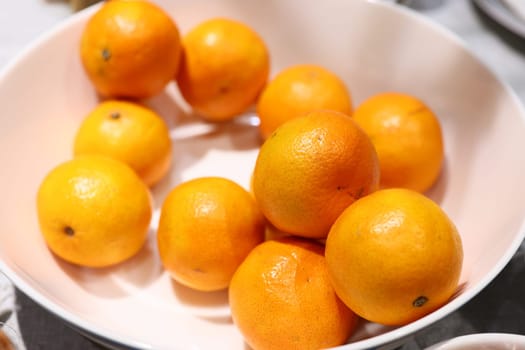 A beautifully vibrant display of fresh, juicy oranges arranged neatly in an elegant white bowl for everyone to admire