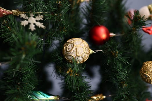 A closeup view of a beautifully decorated Christmas tree adorned with vibrant red, gold, and green ornaments