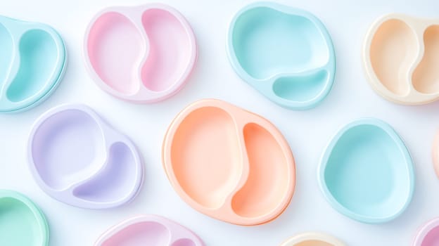 Several pastel colored silicone baby plates with suction cups are arranged on a white background. Creating a visually appealing pattern. Promoting safe and enjoyable mealtimes for babies and toddlers