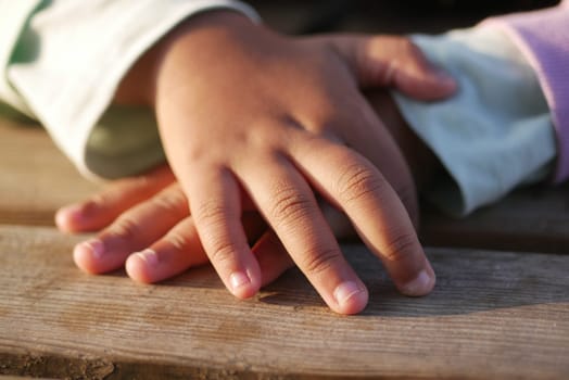 Childrens small hands rest on smooth wood, showcasing their innocence and connection