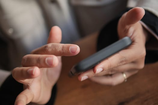 Two hands engaging with a mobile device placed on a rustic wooden table surface