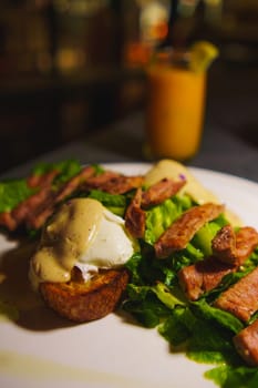 Gourmet steak and poached eggs on a bed of lettuce, served on a dark plate with a blurred background in the cafe