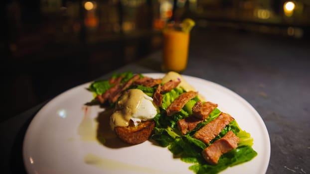 Gourmet steak on lettuce with sauce on a white plate, blurred bar background in the night