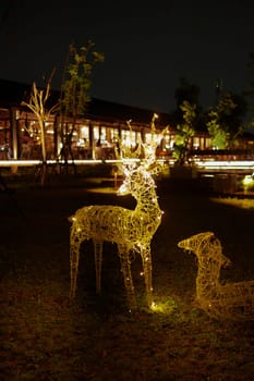 Illuminated deer-shaped Christmas lights at night with buildings in the background.