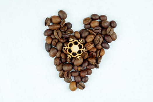Roasted coffee beans arranged in a heart shape with a wooden snowflake in the center on a white background, creating a festive and minimalistic design.