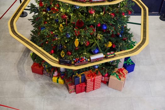 A beautifully decorated Christmas tree that is elegantly adorned with colorful gifts and a charming toy train