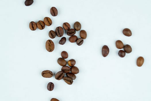 A minimalistic arrangement of roasted coffee beans spread irregularly on a plain white surface, emphasizing simplicity and natural texture.