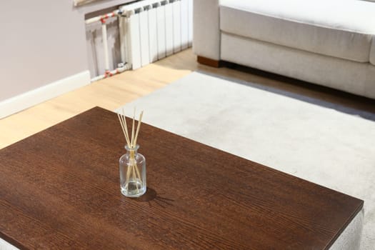 This stylish living room showcases a beautifully designed, sleek wooden coffee table alongside a decorative diffuser