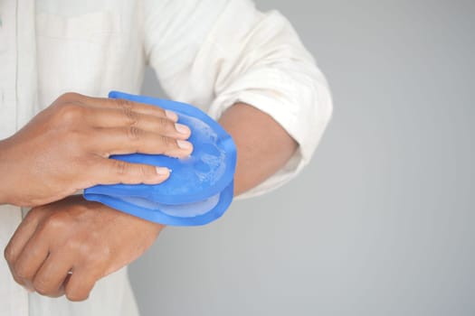 Person Applying Blue Ice Pack to Their Arm for Pain Relief or Injury.