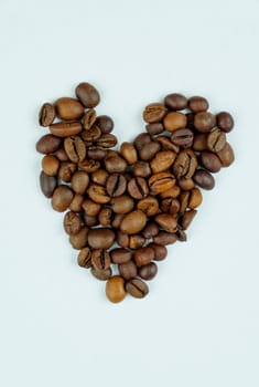 A simple and artistic arrangement of roasted coffee beans forming a heart shape on a plain white background, symbolizing a love for coffee.