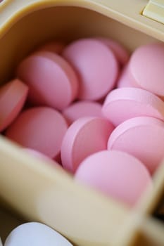 A closeup photo shows neatly arranged pink pills in a container, highlighting their color