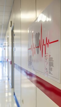 Poster detailing signs and symptoms of arrhythmias displayed in a hospital corridor, emphasizing medical education and patient awareness. the design features a heartbeat line, supporting healthcare communication and information dissemination.