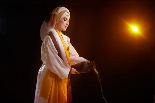 Dressed in vibrant national clothing, a girl stands poised as she pours water, embodying the biblical character Rebekah in a meaningful portrayal.