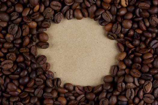 Roasted coffee beans arranged in a circular frame around blank kraft paper, ideal for text or designs, creating a natural and rustic composition, no people.