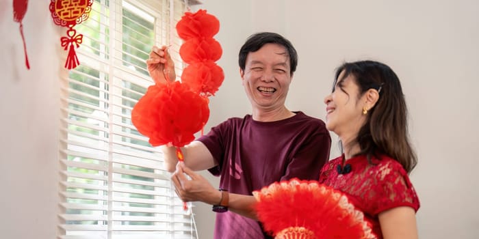 An elderly Chinese couple joyfully prepares for the New Year showcasing their love and cultural traditions.