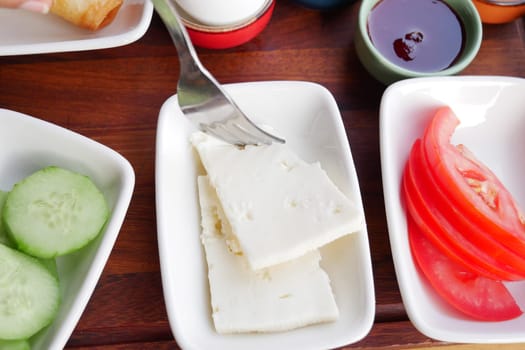 A vibrant assortment of fresh vegetables and cheeses on a wooden platter, perfect for sharing