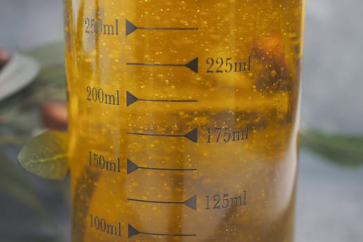 A closeup shows oil in a measuring jug with clear markings for easy cooking or baking