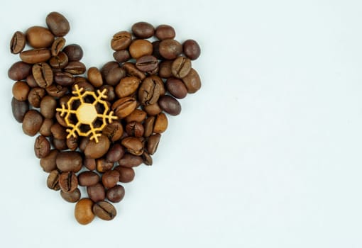 Roasted coffee beans arranged in a heart shape with a decorative wooden snowflake in the center on a clean white background.