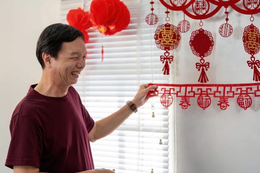 An elderly Chinese couple joyfully prepares their home for the New Year embracing cultural traditions and festive decorations.