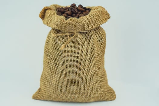 A burlap sack tightly filled with roasted coffee beans, standing upright on a white background, showcasing rustic packaging and texture.