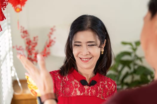 An elderly Chinese couple joyfully celebrates Chinese New Year at home enjoying the festive atmosphere together.