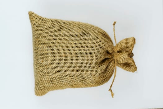 A rustic burlap sack tied with twine placed on a clean white background, emphasizing texture and simplicity in a minimalistic design.