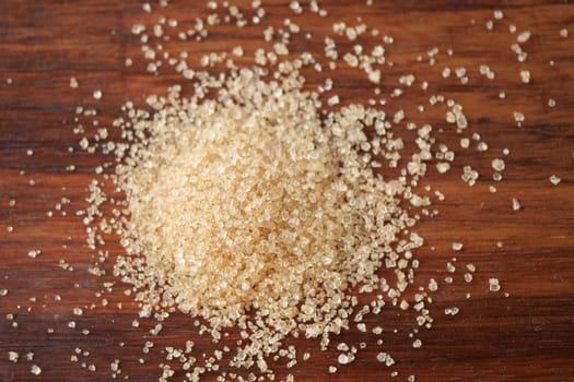 Here is a detailed closeup view of brown sugar granules spread out on a rustic wooden background