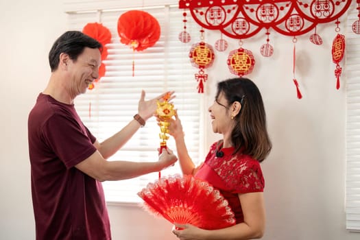 Elderly couple joyfully celebrate Chinese New Year together exchanging gifts and enjoying cultural traditions.