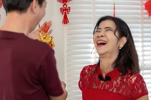 An elderly couple joyfully celebrates Chinese New Year embodying love and tradition in a festive home atmosphere.