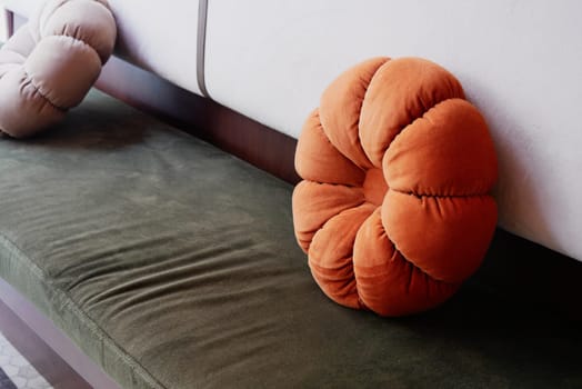 There are two unique, beautifully designed decorative pillows placed on a stylish green sofa