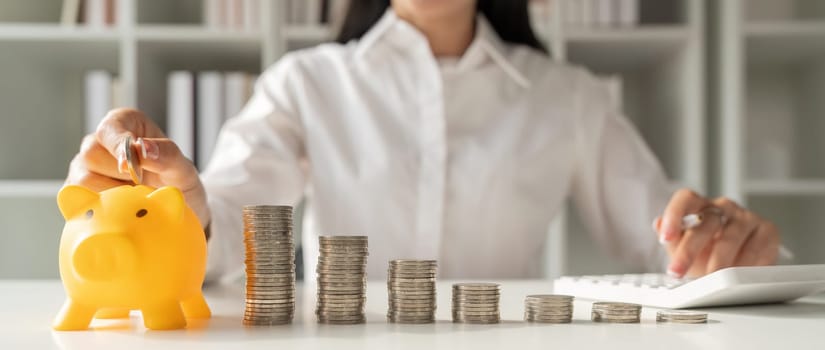 Saving money. young woman asian putting a coin into a money piggy bank.